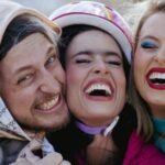 Three friends laughing joyfully outdoors, capturing happy moments together.