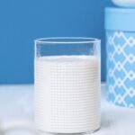 A clean and simple still life featuring a glass of milk with blue decor, offering a serene aesthetic.