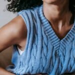 Young African American female sitting on couch at home while having acute pain in stomach