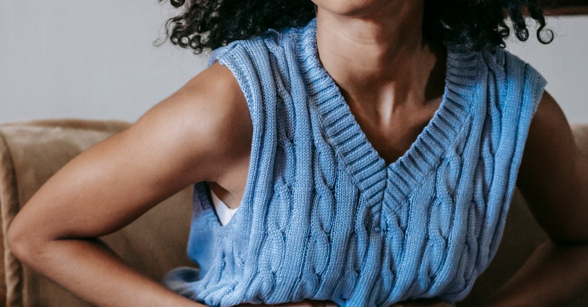 Young African American female sitting on couch at home while having acute pain in stomach