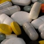 A diverse collection of pills and capsules in various colors on a dark background, emphasizing health and medicine.