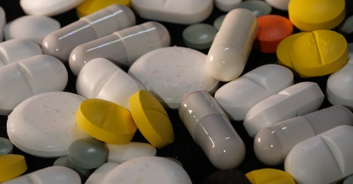 A diverse collection of pills and capsules in various colors on a dark background, emphasizing health and medicine.