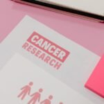 Assorted cancer research materials laid on a pink desk. Professional workspace.