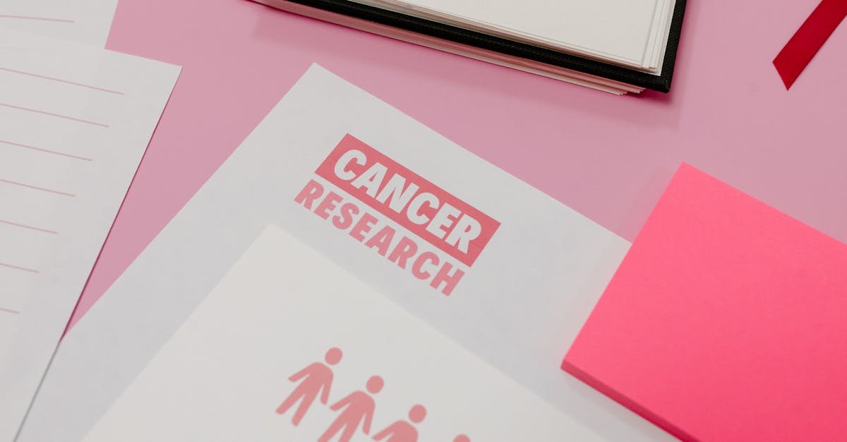 Assorted cancer research materials laid on a pink desk. Professional workspace.