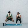 Man and woman exercising outdoors on a yoga mat, focusing on squats and healthy lifestyle.